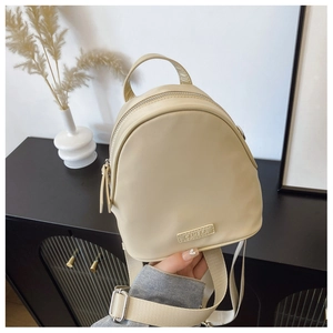 Close-up of cream-white mini backpack with silver metal adjusters and brand name tag