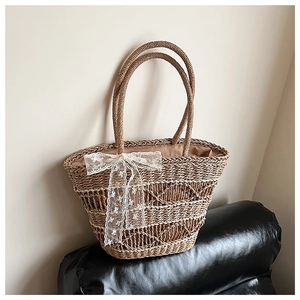 Detailed close-up of handmade straw tote bag with delicate white lace bow and woven texture
