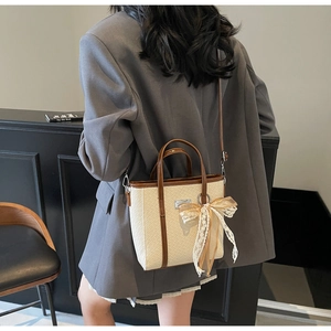Vista dettagliata di una borsa a secchiello intrecciata con finiture marroni e pizzo