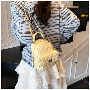 Rear view of a model wearing a beige quilted mini backpack on a modern staircase