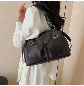 Detail of dark brown vintage faux leather tote with textured finish and metal ring buckles