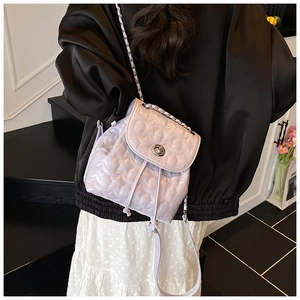 Rear view of a model wearing the light purple mini backpack with star quilting and chain straps