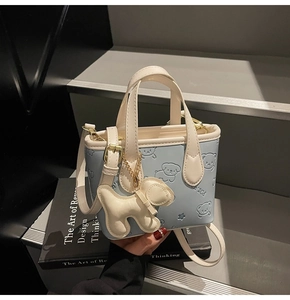 Détail du sac seau bleu clair avec motifs d'ours en relief et accessoire de chiot