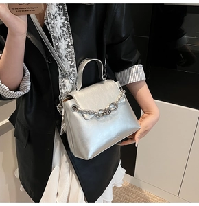 Detail of silver metallic crossbody bag with chunky chain and knot metal decoration