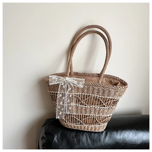 Detailed view of natural woven texture on straw tote bag with white lace bow decoration