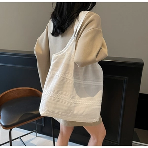 Detailed side view of white canvas tote bag with horizontal texture on female model