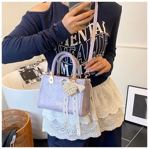 Detail of lavender pleated crossbody bag with woven handle and heart pearl charm accessory