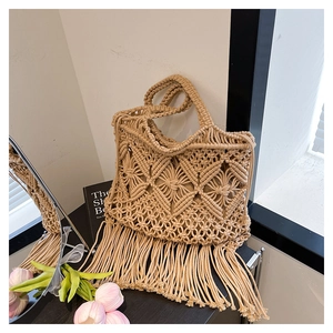 Detail of handmade beige macrame tote bag featuring intricate diamond patterns and long tassels