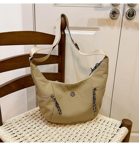 Détail du sac hobo beige avec logo métallique M et poches zippées latérales pratiques
