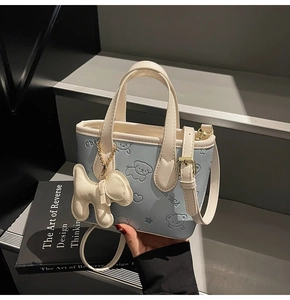 Détail du mini sac seau bleu clair avec chiens de dessin animé embossés et dorure