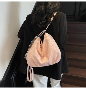 Pale pink marbled tote bag worn by model, featuring fringe detail and adjustable strap