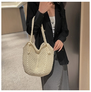 Detail of hand-woven hollow mesh tote bag with fringe accents and braided straps