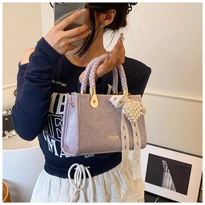 Detail of lavender pleated PU handbag with woven handle and lace pearl butterfly charm