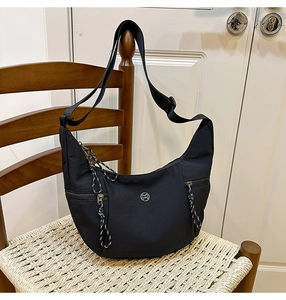 Gros plan détaillé d'un sac hobo en nylon noir avec poches zippées et logo M discret