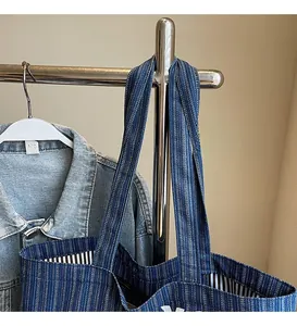 Detail of the smooth long shoulder straps on this striped denim tote bag