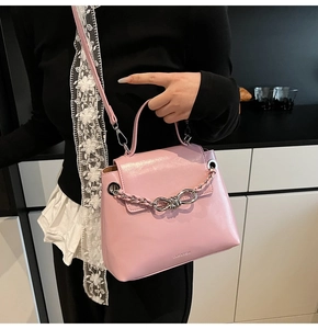 Detail of glossy pink leather handbag featuring a silver bow chain and CEUAROK embossing