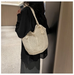 Detail of cream crochet tote bag with woven hollow mesh and bohemian tassel charm