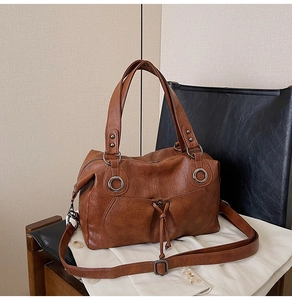 Detailed close-up of retro brown leather tote with silver metal rings and textured surface