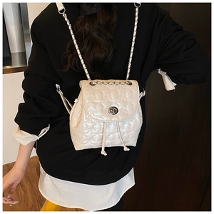 Detail of white star-quilted backpack showing metallic clasp and chain shoulder strap