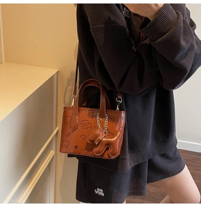 Gros plan d'un sac seau marron en similicuir avec imprimé chien porté par un mannequin