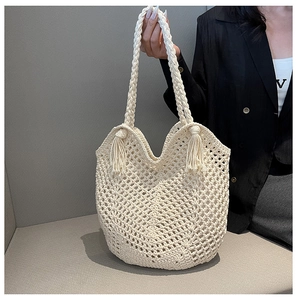 Detail of cream handmade crochet tote bag featuring hollow mesh and tassel accents
