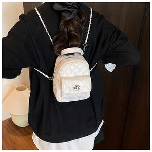 Detail of white quilted backpack with silver metal twist lock and chain strap links