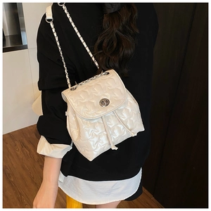 Detail of pearl white star-quilted backpack with silver metal buckle and chain straps