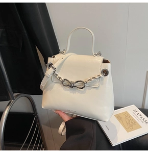 Close-up of white leather handbag with silver metal bow chain and elegant top handle