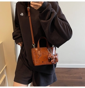 Détail d'un sac à main en cuir gaufré avec motifs d'ours et breloque portée