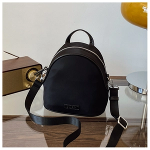 Detail of black mini shell backpack with leather handle and adjustable crossbody strap
