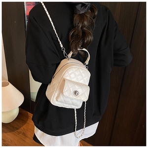 Detailed view of a white quilted mini backpack with chain strap on a black sweater