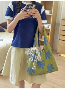 Detail of green nylon hobo bag with blue floral print and white lace bow decoration