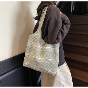 Detail of a large capacity checkered canvas tote bag with woven stripe decorative accents