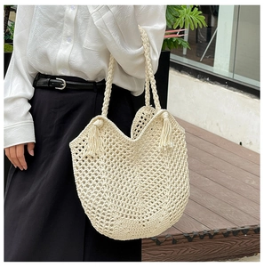 Détail du sac de plage en crochet crème avec des glands décoratifs et des anses tressées