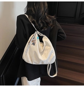 Detail of white marble textured tote bag with a cute bear charm on a wood staircase