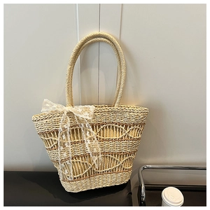 Detail of hand-woven straw tote bag with a large white lace bow in a cozy indoor setting