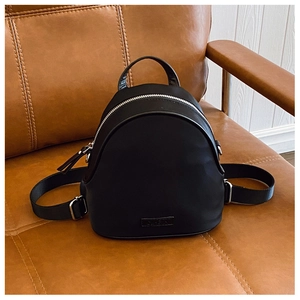 Detail of black mini backpack with silver metal zippers on vintage leather background