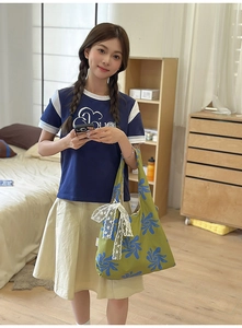 Green nylon dumpling bag with blue floral print and white lace bow detail