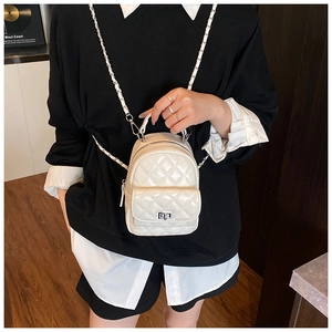 Detailed view of a white quilted mini backpack with chain strap on a model's back