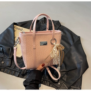 Dettaglio della borsa a secchiello rosa chiaro con trama intrecciata e fiocco in pizzo