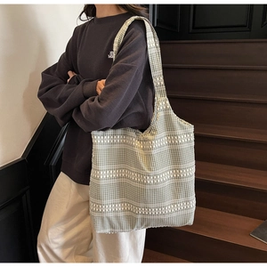 Green and white checkered canvas tote bag shown on a model by wooden stairs