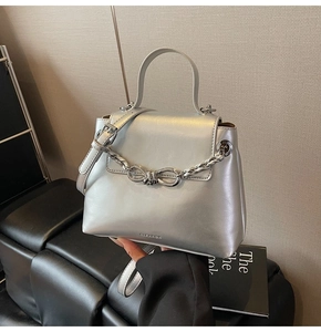 Detail of silver metallic shoulder bag with knot chain and elegant branded logo