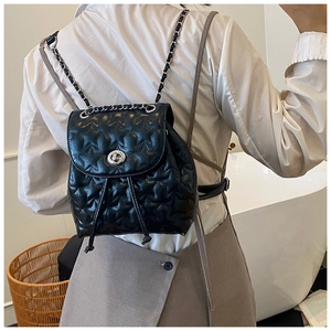 Detail of star-quilted black mini backpack with silver twist lock and chain straps