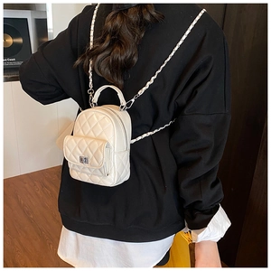 Close-up of white quilted mini backpack with silver chain strap worn by a model