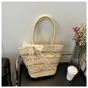 Detailed texture of hand-woven straw tote bag with white lace ribbon bow decor