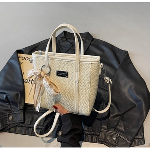 Dettaglio borsa a mano intrecciata crema con nastro in pizzo e placca in metallo moda