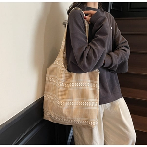 Side view of a yellow gingham canvas tote bag worn on shoulder in a minimalist setting