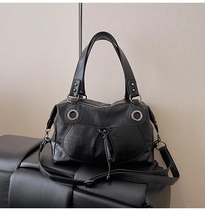 Detail of black faux leather tote with silver eyelets and bohemian drawstring elements