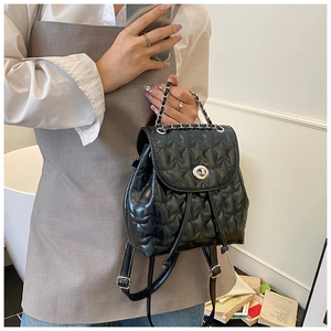 Detail of black star-quilted backpack featuring silver chain handle and metal twist lock
