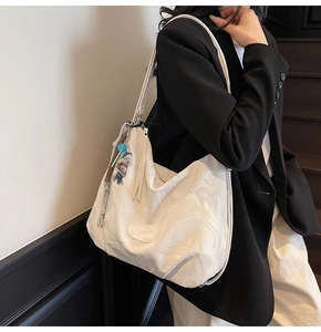 Detail of cream marble pattern tote bag with plush charm and polished texture